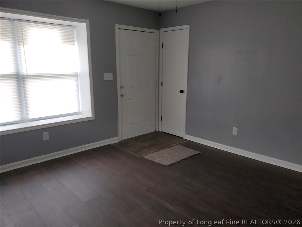 724 Spruce Street Lumberton, NC 28358 - Photo 3 of 13 an empty room with wooden floor and windows