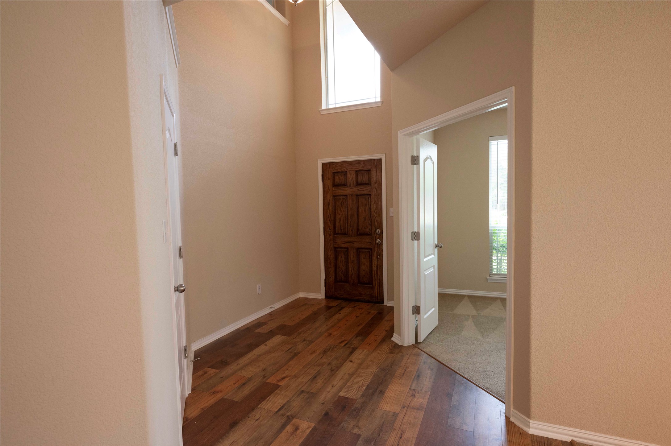 2070 Intrepid Drive Buda, TX 78610 - Photo 2 of 31 A welcoming entryway with rich wood flooring flows into adjacent living spaces, crowned by high ceilings.