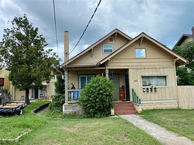 a view of a house with a yard and a large tree