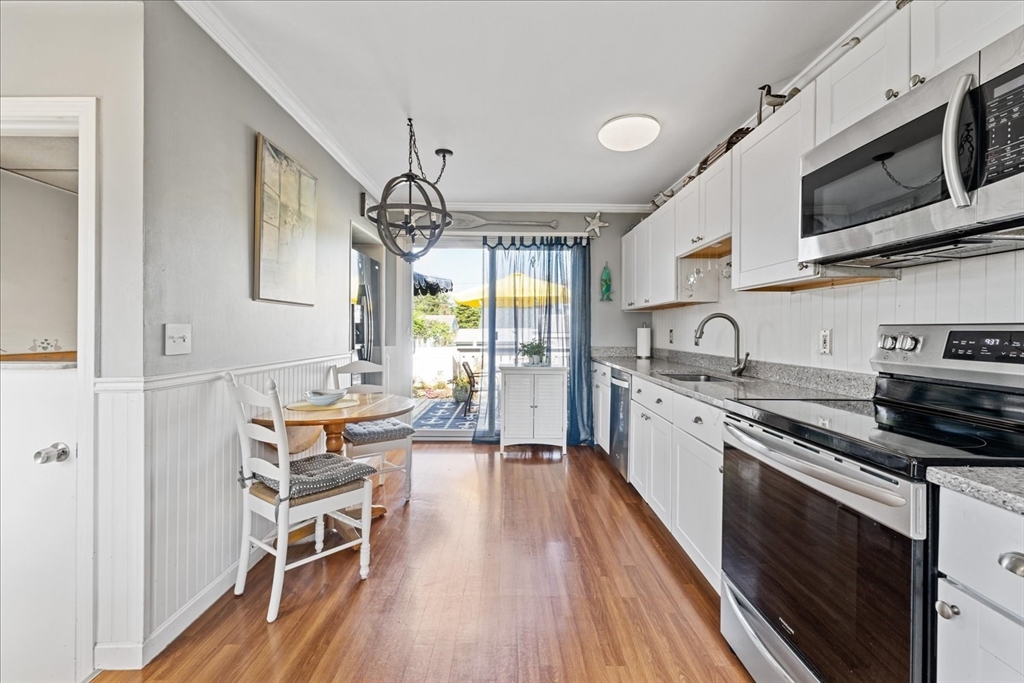 45 Tupelo Road South Kingstown, RI 02879 - Photo 8 of 28 a kitchen with stainless steel appliances a stove a sink dishwasher a microwave oven and a dining table with wooden floor