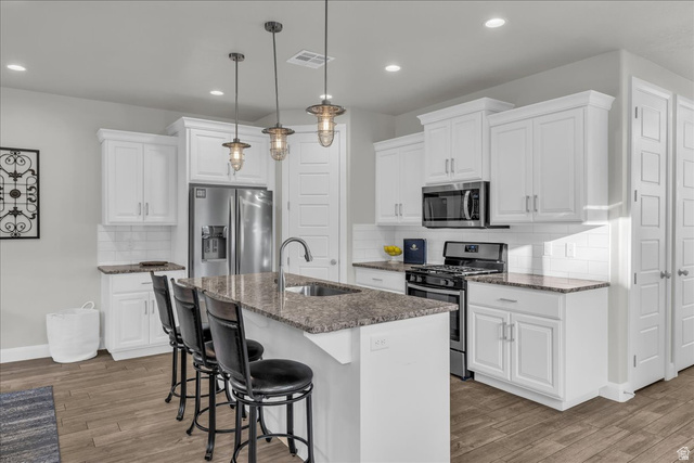 4796 Winged Foot Drive St. George, UT 84770 - Photo 22 of 33 Kitchen with stainless steel appliances, a kitchen breakfast bar, and white cabinets