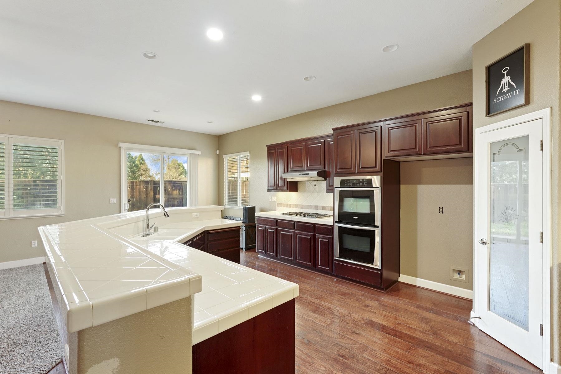 2644 Swainsons Hawk Street Stockton, CA 95209 - Photo 9 of 41 a kitchen with stainless steel appliances kitchen island granite countertop a refrigerator a stove top oven a sink and dishwasher with wooden floor