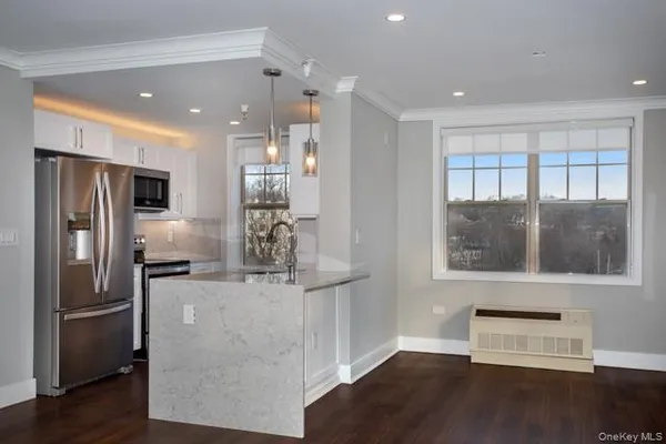 a kitchen with stainless steel appliances granite countertop a refrigerator and a stove top oven with wooden floor