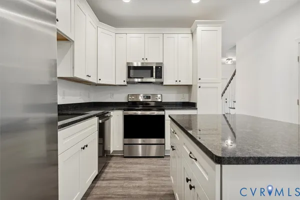 a kitchen with granite countertop a sink stainless steel appliances and white cabinets