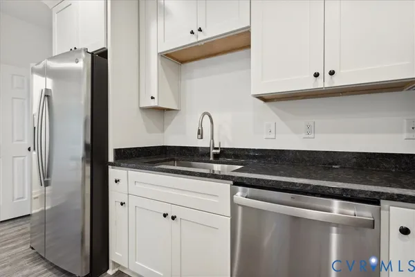 a kitchen with granite countertop white cabinets and stainless steel appliances