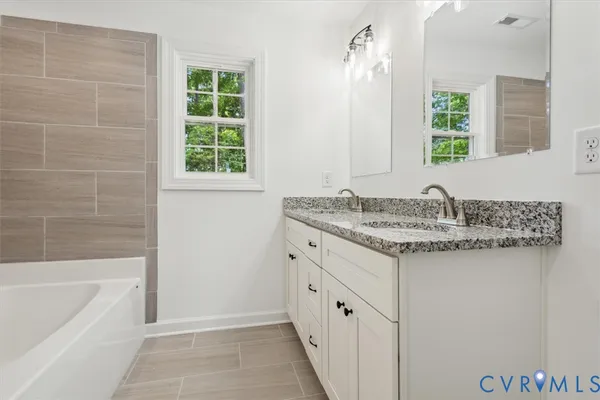 a bathroom with a granite countertop sink and a bathtub
