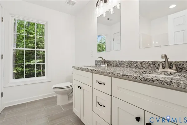 a bathroom with a granite countertop sink mirror vanity and toilet