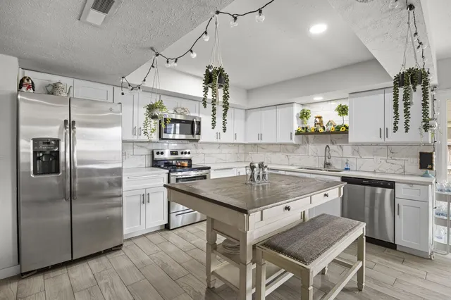a kitchen with kitchen island a counter top space appliances and cabinets