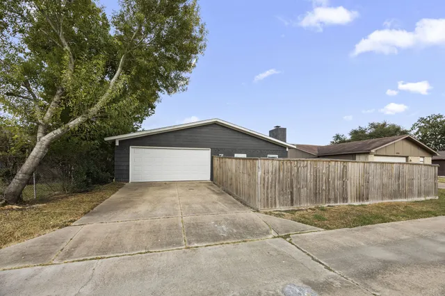 a view of backyard of house with wooden fence