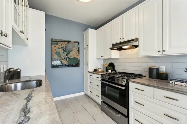 a kitchen with stainless steel appliances granite countertop white cabinets and a stove