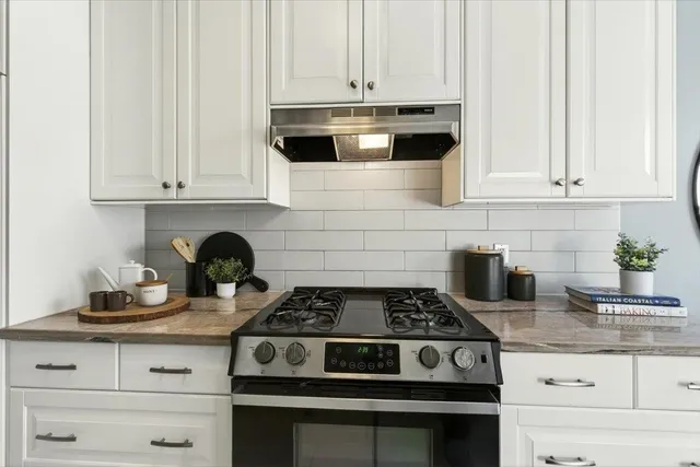 a kitchen with granite countertop white cabinets and stainless steel appliances