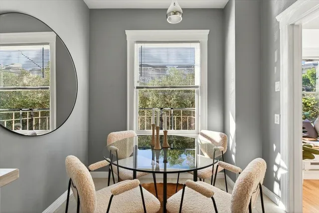 a view of a dining room with furniture a potted plant and a window