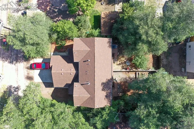 an aerial view of residential house with outdoor space and trees all around