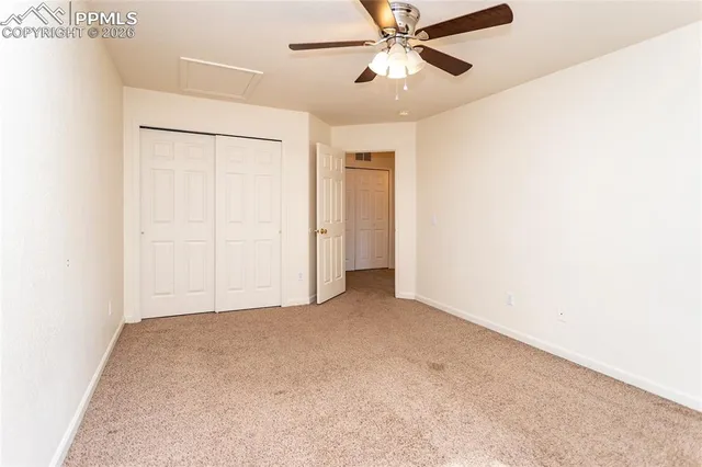 an empty room with closet and a chandelier fan