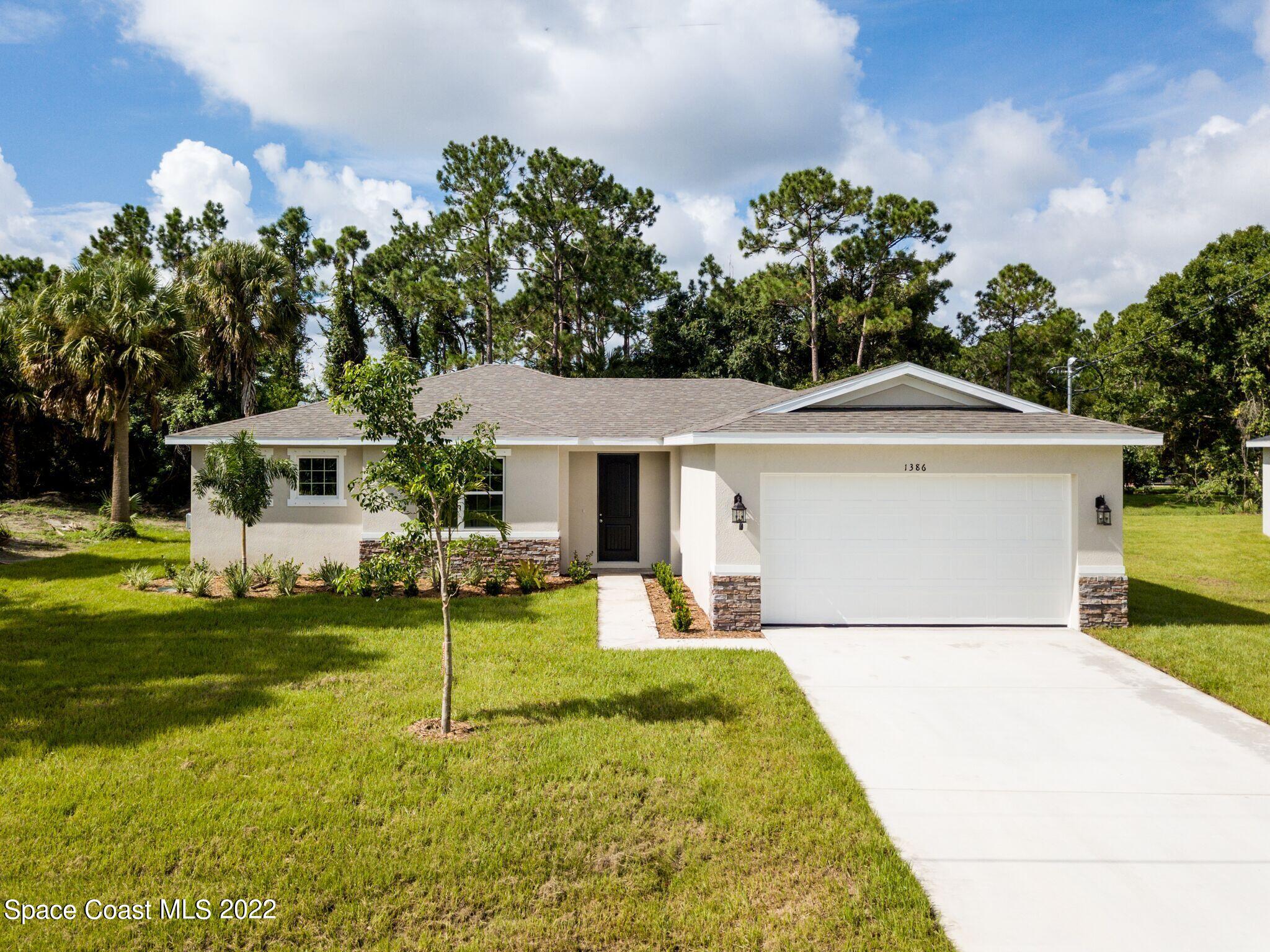 1376 Wing Road Southwest Palm Bay, FL 32908 - Photo 1 of 17 a front view of a house with a garden and trees