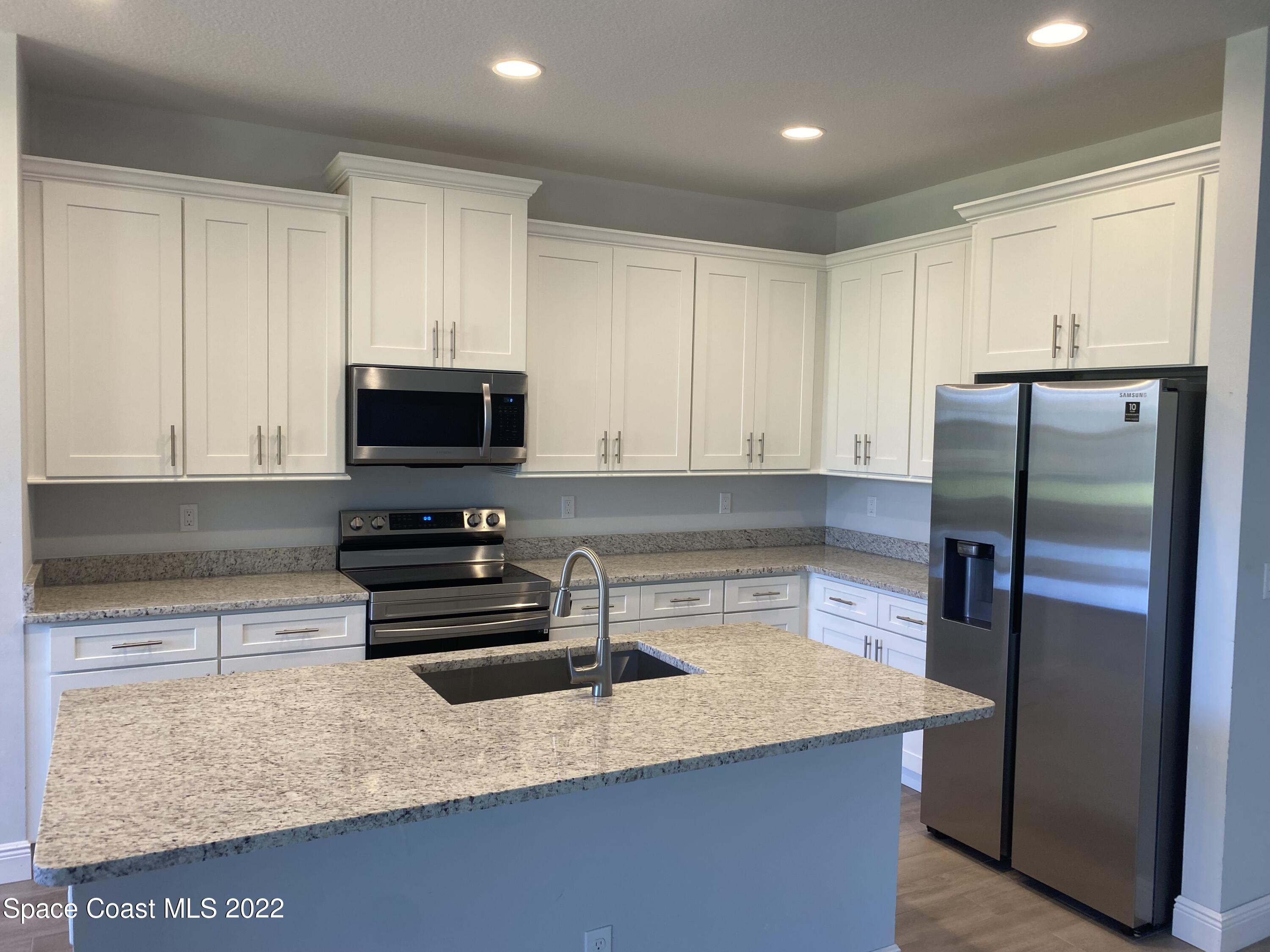 1376 Wing Road Southwest Palm Bay, FL 32908 - Photo 5 of 17 a kitchen with stainless steel appliances granite countertop a refrigerator a stove a sink and a microwave