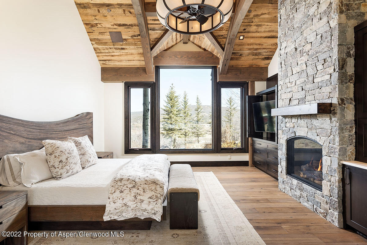 2322 Lazy O Road Snowmass, CO 81654 - Photo 11 of 42 a bedroom with a large bed and a fireplace