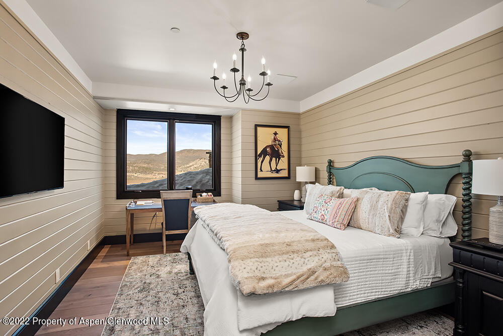 2322 Lazy O Road Snowmass, CO 81654 - Photo 17 of 42 a bedroom with a large bed and a chandelier