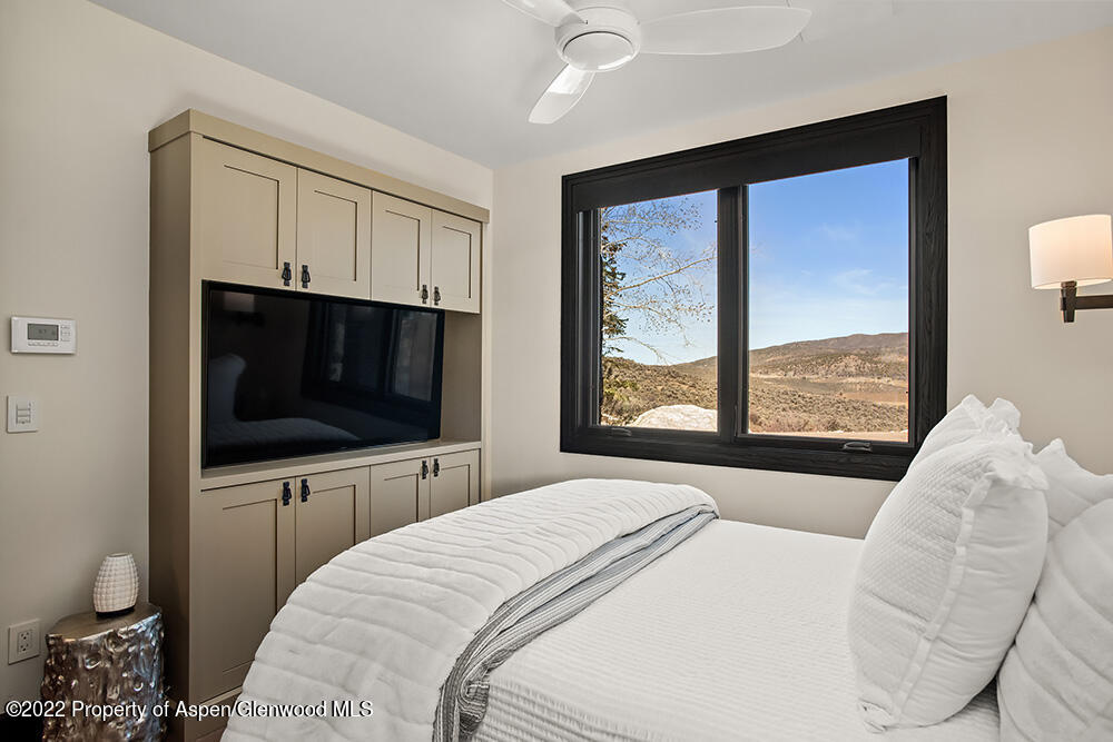 2322 Lazy O Road Snowmass, CO 81654 - Photo 24 of 42 a bedroom with a large bed and a flat tv screen on dresser