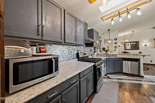 a kitchen with stainless steel appliances granite countertop a stove a sink and a microwave