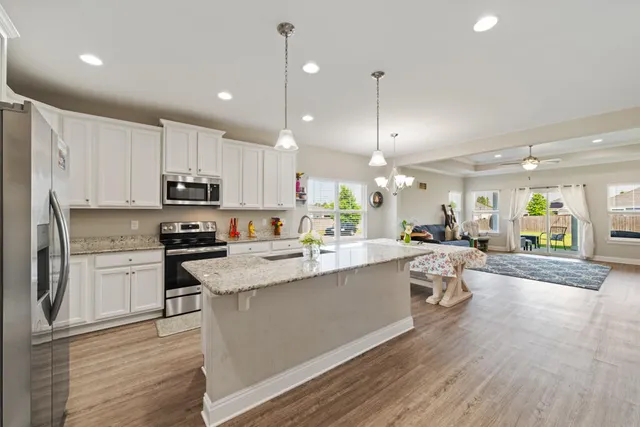 a large white kitchen with lots of counter space a sink appliances and cabinets