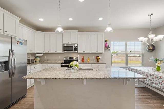 a kitchen with stainless steel appliances granite countertop a sink a stove a refrigerator a center island a stove and cabinets