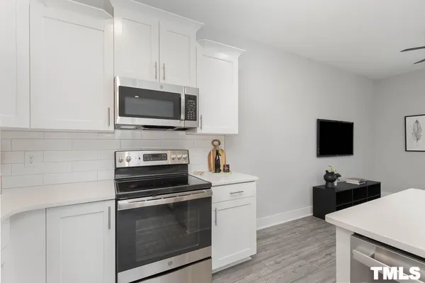 a kitchen with cabinets stainless steel appliances and wooden floor
