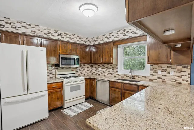 a kitchen with stainless steel appliances granite countertop a stove refrigerator sink and microwave