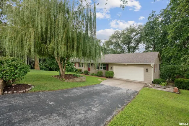 a view of a house with a yard and large tree