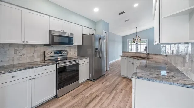 a kitchen with stainless steel appliances granite countertop a stove a sink and a refrigerator