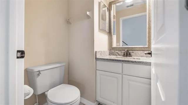 a bathroom with a granite countertop toilet sink and mirror