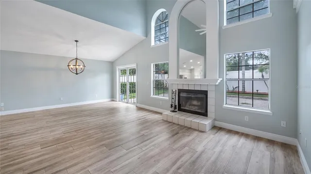 an empty room with wooden floor fireplace and windows