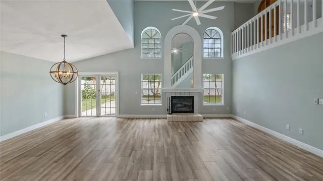 a view of empty room with wooden floor fireplace and fan