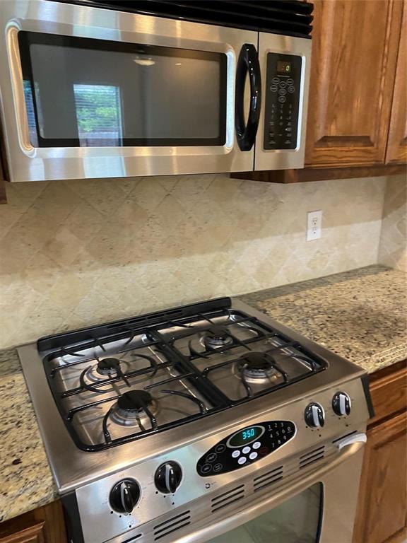 2222 Kirby Street Dallas, TX 75204 - Photo 16 of 25 Stainless steel range with four gas burners and an integrated oven, complemented by a matching stainless steel microwave