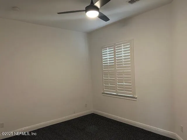 an empty room with a window and a fan