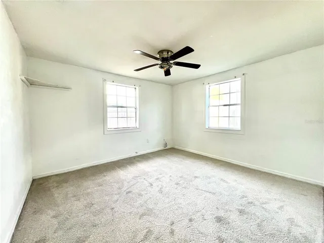 an empty room with windows and ceiling fan