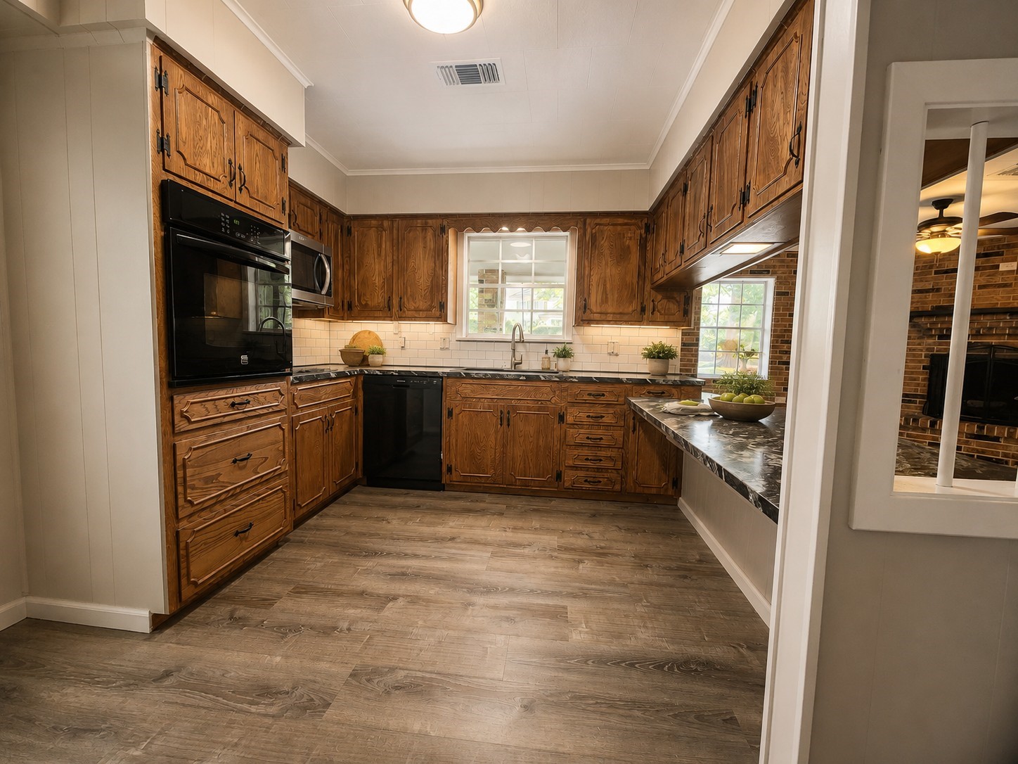 201 Verna Street Jasper, TX 75951 - Photo 9 of 24 This kitchen features rustic wooden cabinets, modern appliances, and a stylish tile backsplash. The open layout includes a large window for natural light and a serving counter that connects to the living area with a cozy fireplace.