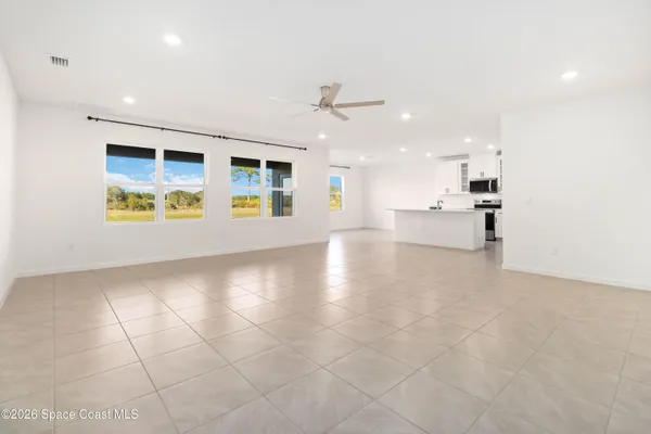 an empty room with ceiling fan and window