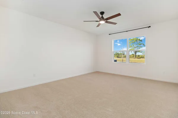 an empty room with a window and a ceiling fan