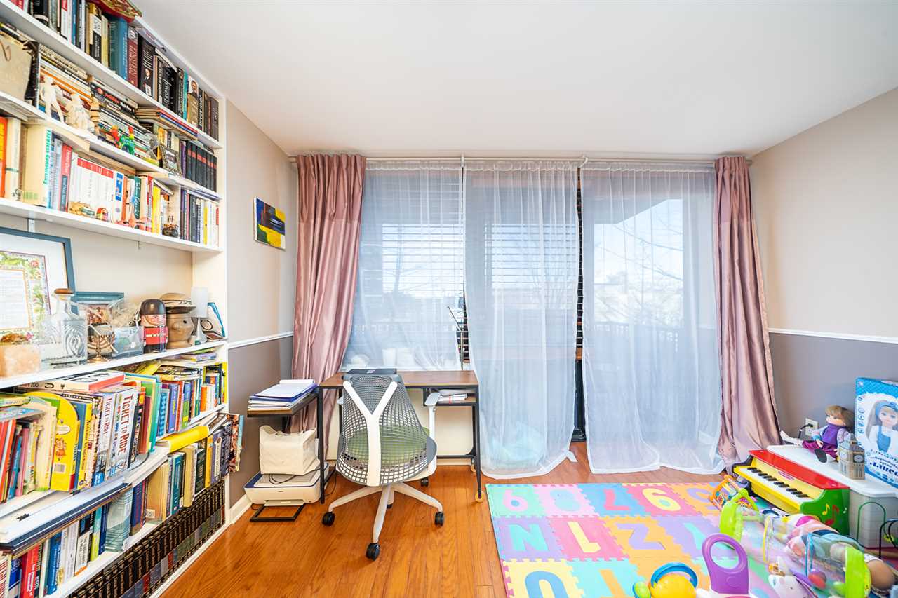 700 Grove Street, Unit 4V Jersey City, NJ 07310 - Photo 10 of 25 a view of a bedroom with baby crib and a book shelf