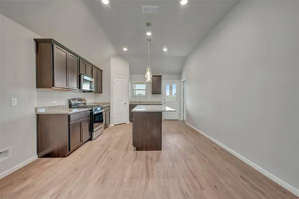 a kitchen with stainless steel appliances granite countertop a stove a sink and a microwave