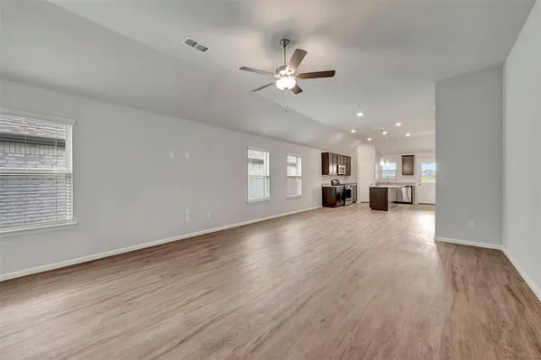 a view of empty room with wooden floor and ceiling fan