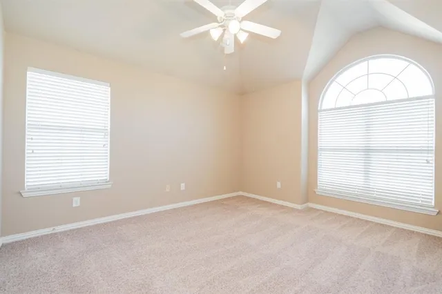 an empty room with a window and a chandelier fan