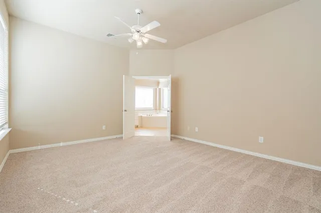 an empty room with a chandelier fan and windows