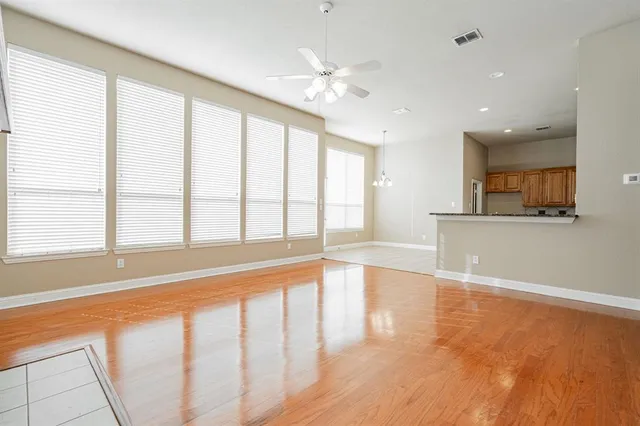 a view of an empty room with window and wooden floor