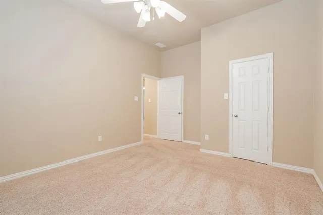 an empty room with a chandelier fan and closet area