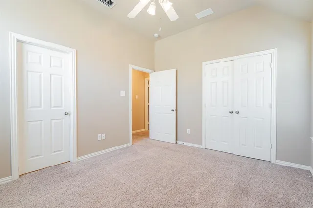an empty room with closet and a chandelier fan