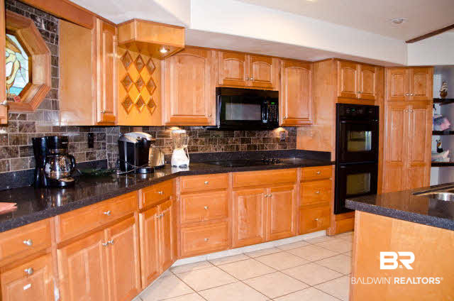 5751 Alabama Street Orange Beach, AL 36561 - Photo 11 of 25 Kitchen with tiled backsplash and granite counters. The kitchen is fully equipped with double oven, microwave, dishwasher, and a NEW stovetop as of 2017.