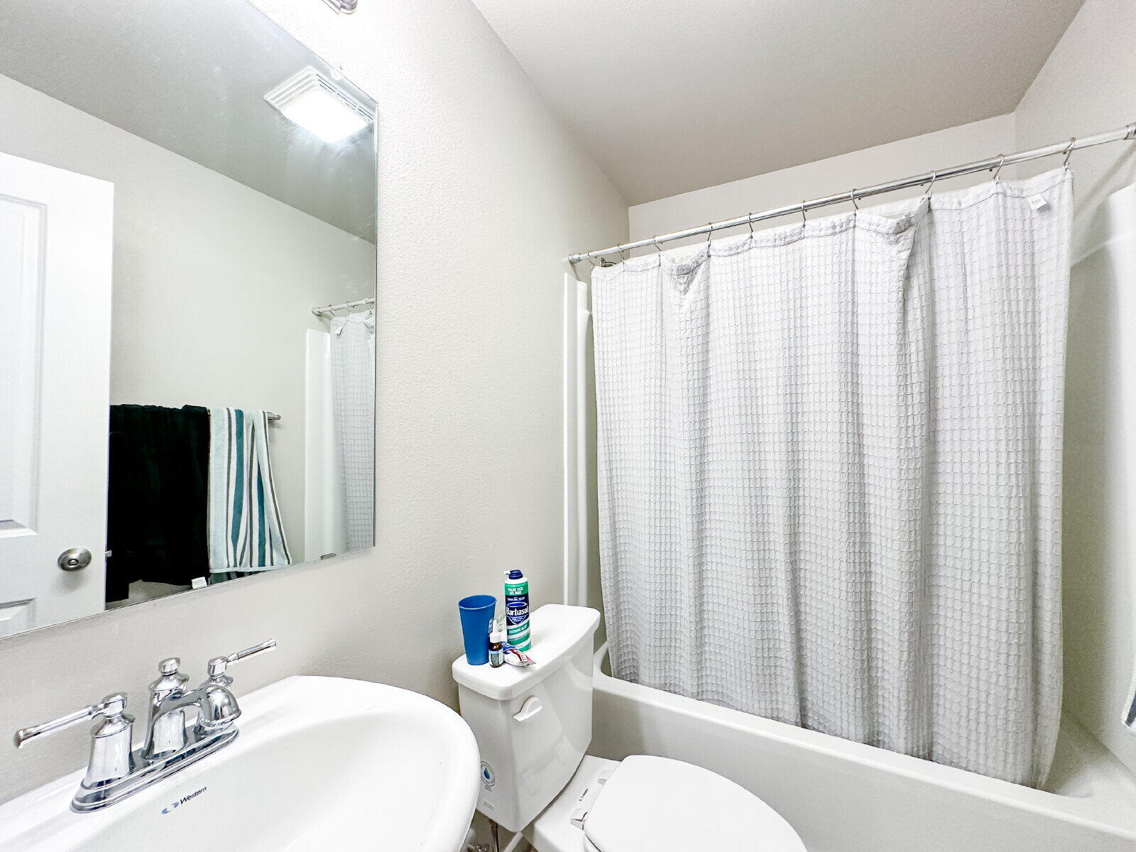 7413 35th Street Lubbock, TX 79407 - Photo 9 of 9 a bathroom with a sink a toilet a mirror and shower curtain