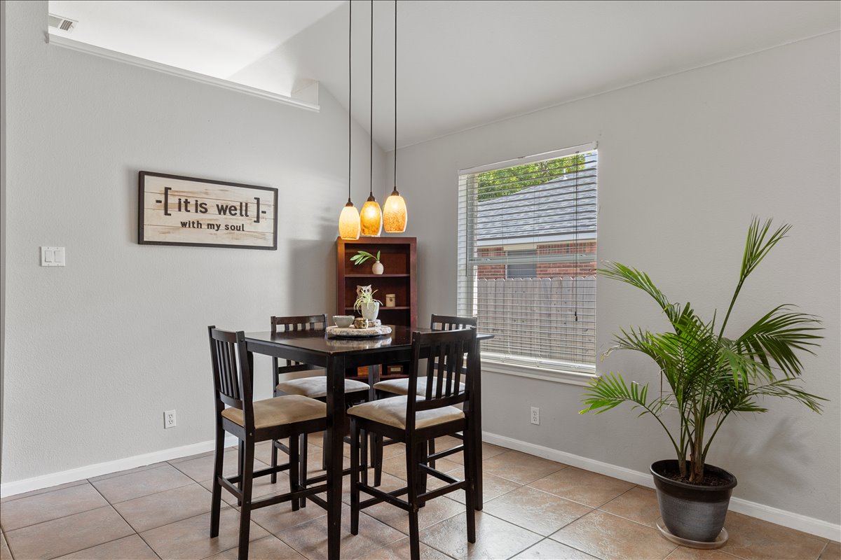 9012 Meacham Way Austin, TX 78749 - Photo 12 of 34 Dining area featuring tile flooring, a vaulted ceiling, and a large window with blinds